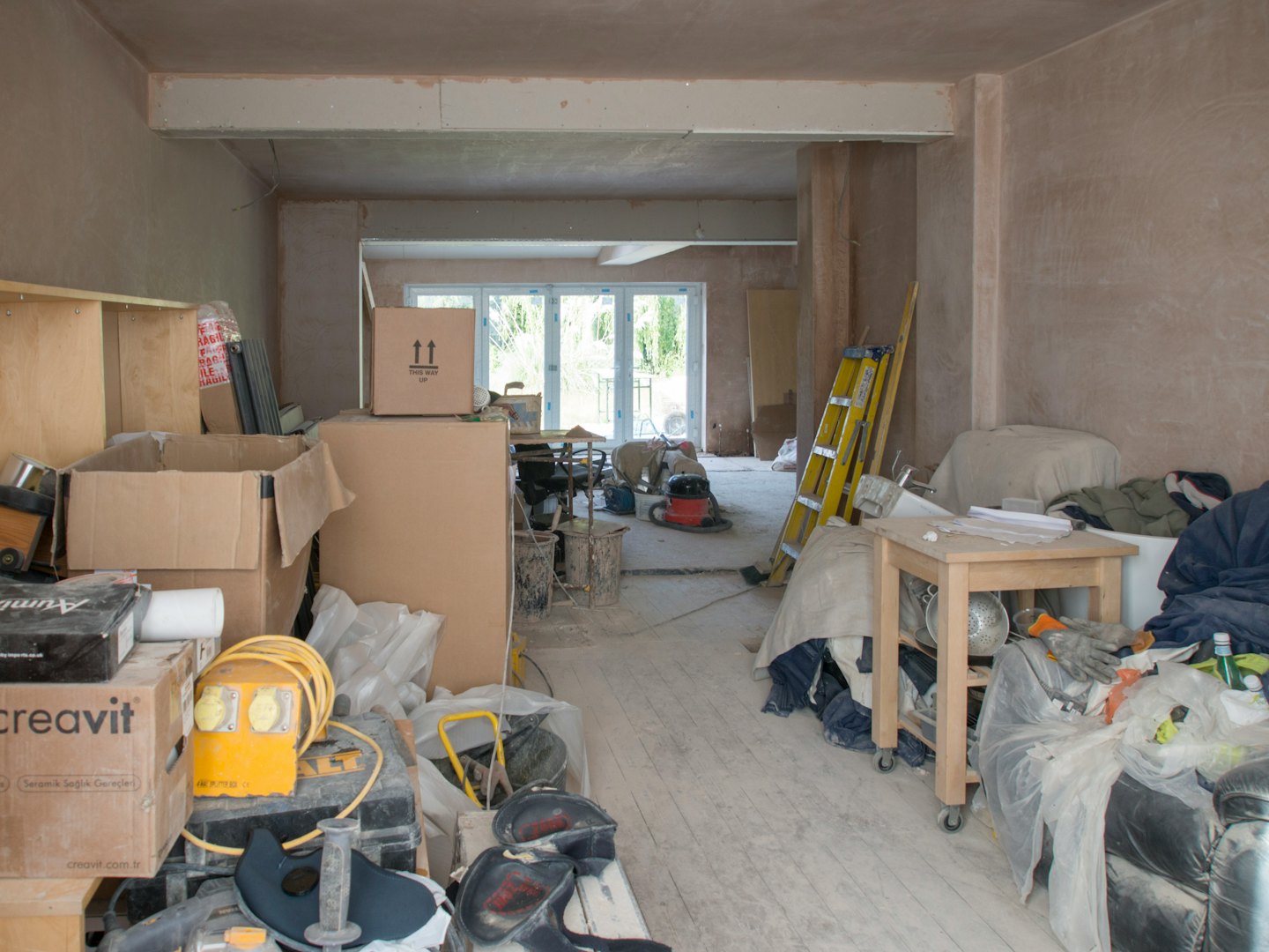Stanza residenziale in ristrutturazione piena di materiali da costruzione e attrezzi.