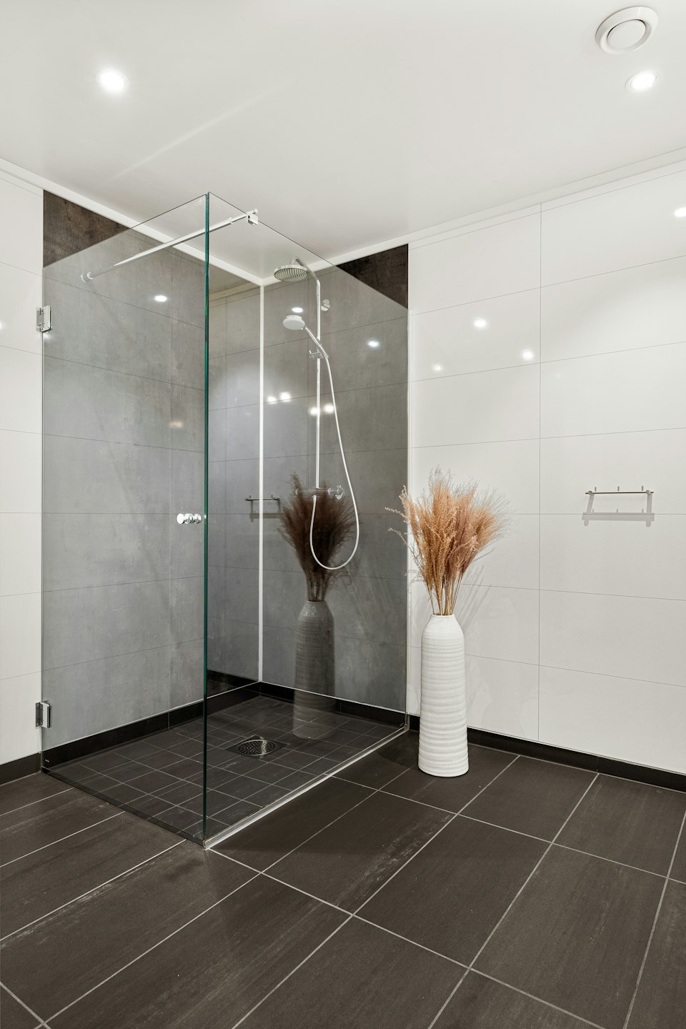 Bagno moderno con doccia in vetro e vaso decorativo a pavimento.